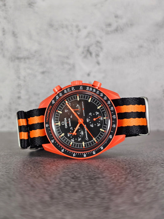 A watch with a black and orange striped strap, featuring a analog display and military-grade brushed stainless steel hardware.