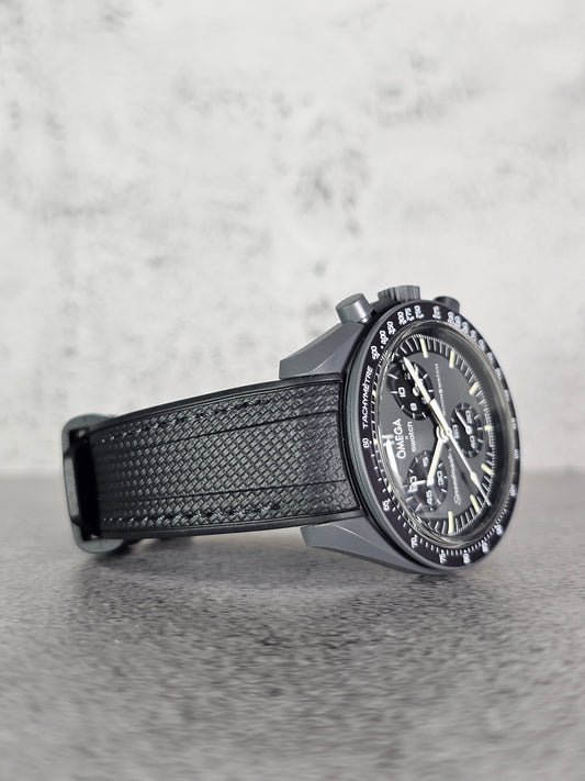 A black stitched rubber woven strap with a curved edge, designed for a watch with a 20mm lug width, displayed on a grey textured background.