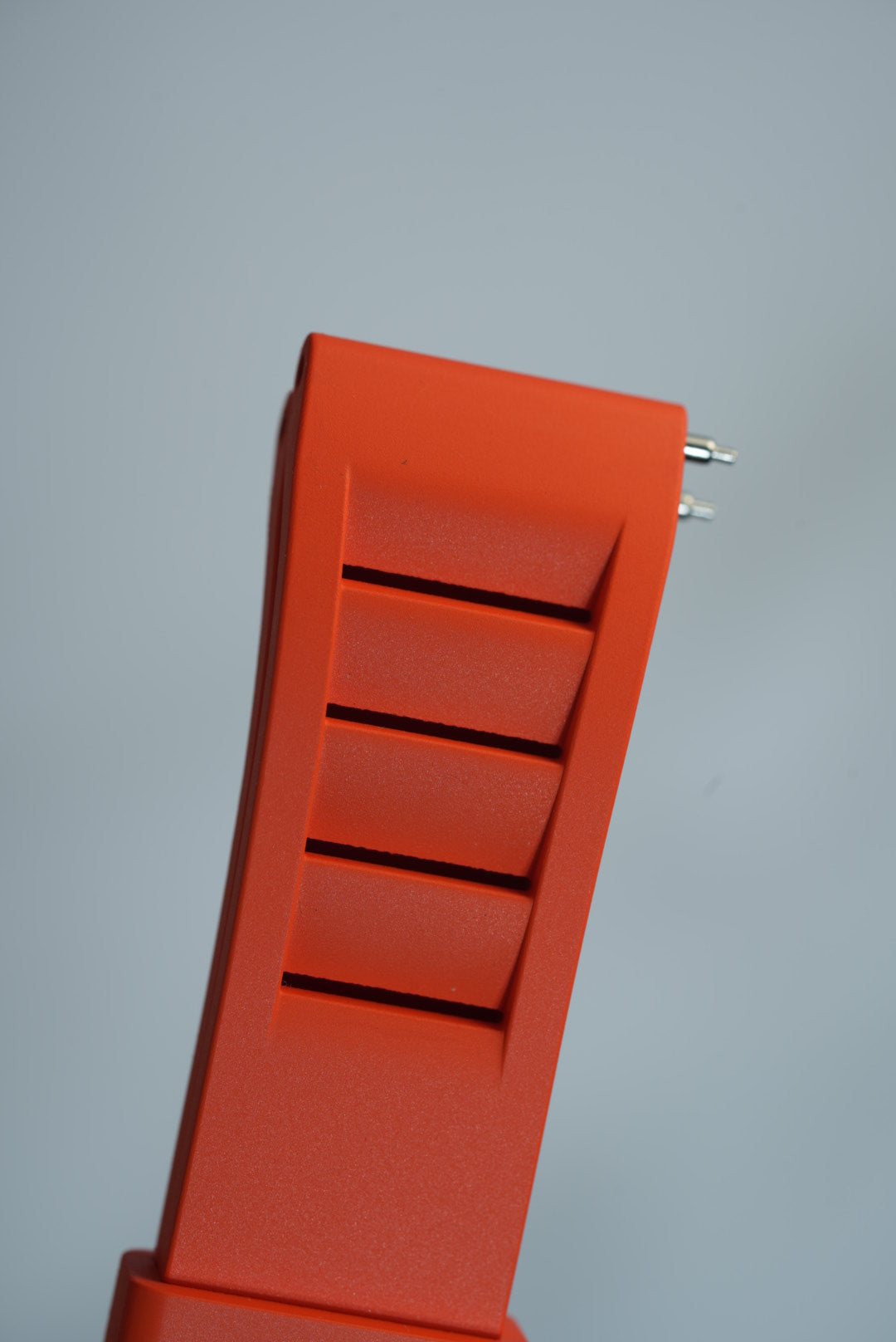 Close-up view of the orange FKM rubber watch strap with vented details, highlighting its flexible and durable construction