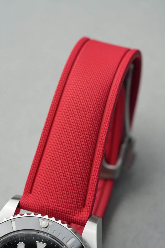 Close-up of a watch with a red strap on a gray background