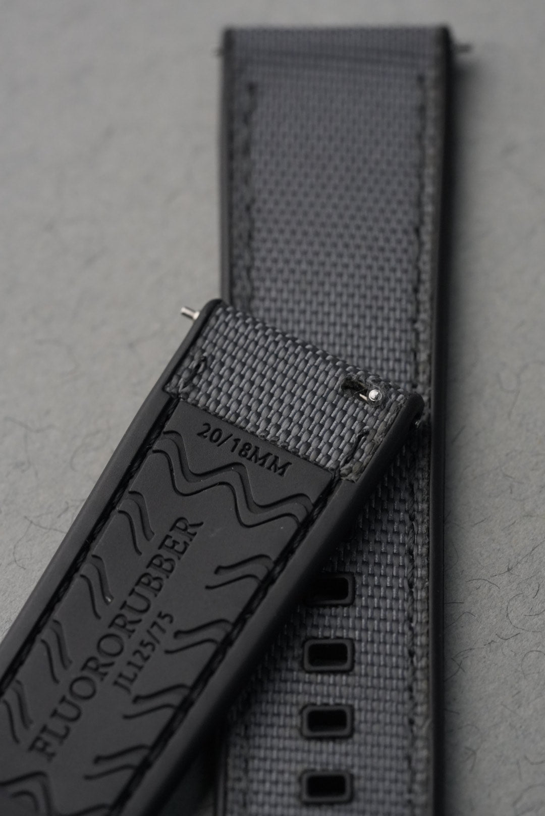 Close-up of a textured black strap with visible branding on a gray background