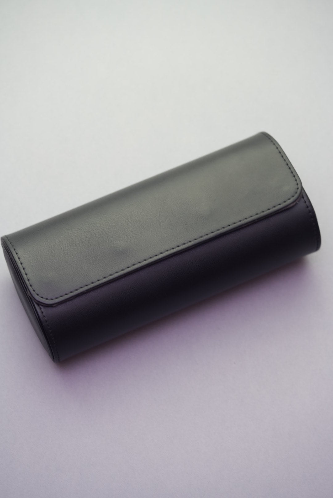 Three-slot black travel watch roll shown closed from a top angle, made with smooth vegan leather.