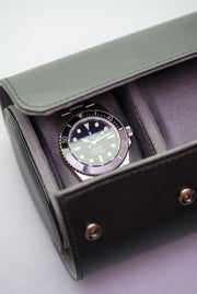 Black watch roll opened to reveal Rolex Submariner resting inside one of the padded compartments.