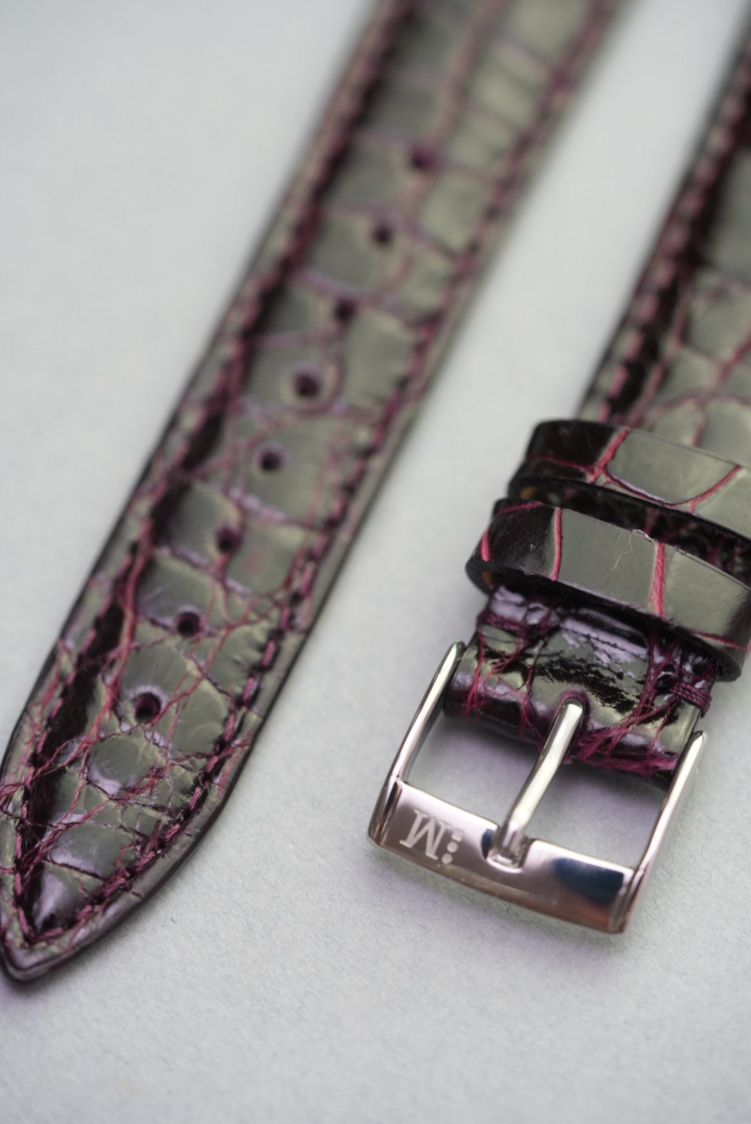 Close-up of the polished stainless steel buckle on the Bordeaux crocodile strap, with vibrant stitching and hand finishing.