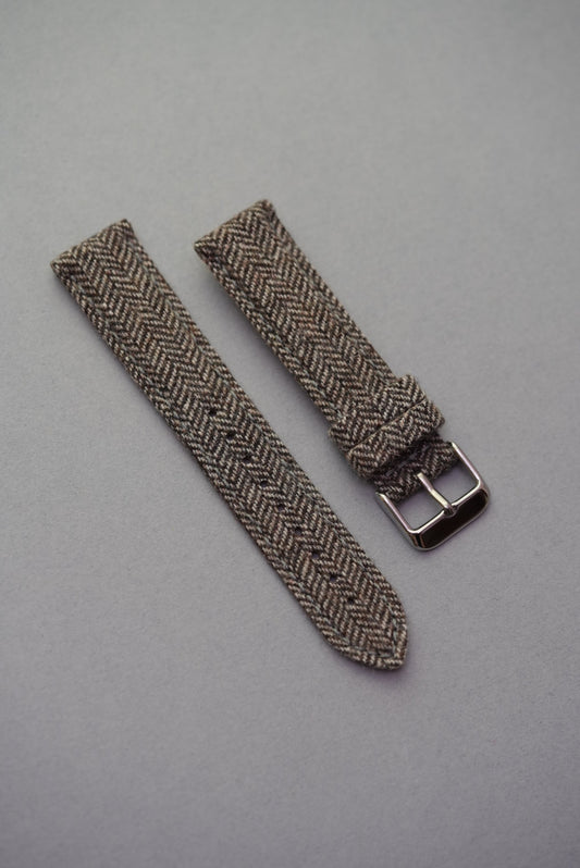 Brown herringbone tweed fabric strap with soft finish and polished buckle, a heritage look for MoonSwatch wearers.