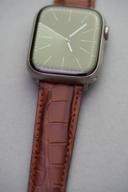 Detailed close-up of adapter fitment on brown alligator embossed strap for Apple Watch