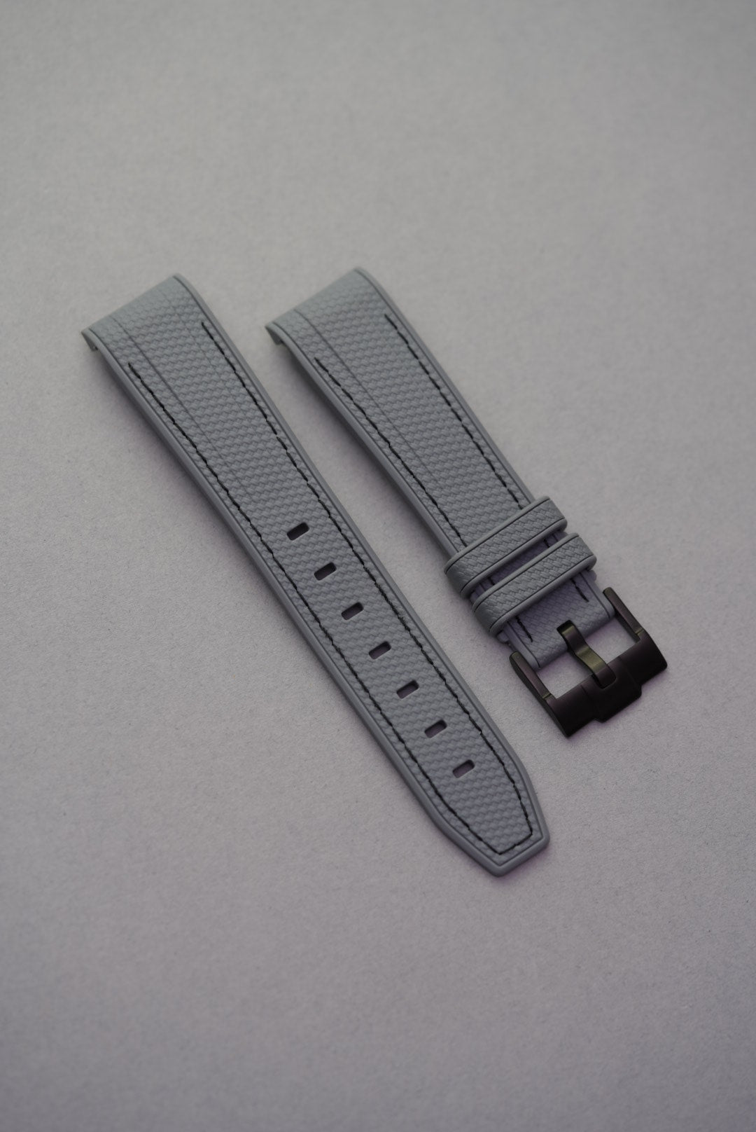 Dark grey curved-end MoonSwatch strap with black stitching, woven texture and matching black buckle.