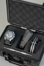 Black open case with a watch, pen, and other items on a light gray background