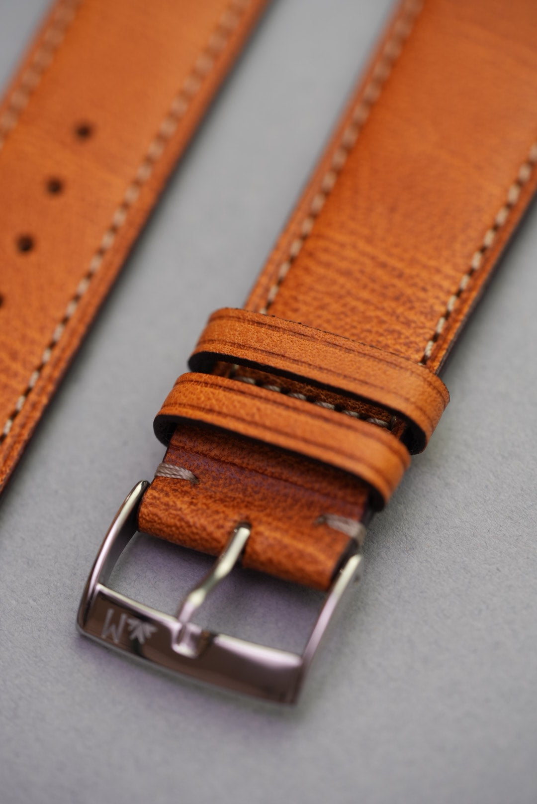 Close-up of golden brown fine grain calfskin leather watch strap with polished buckle