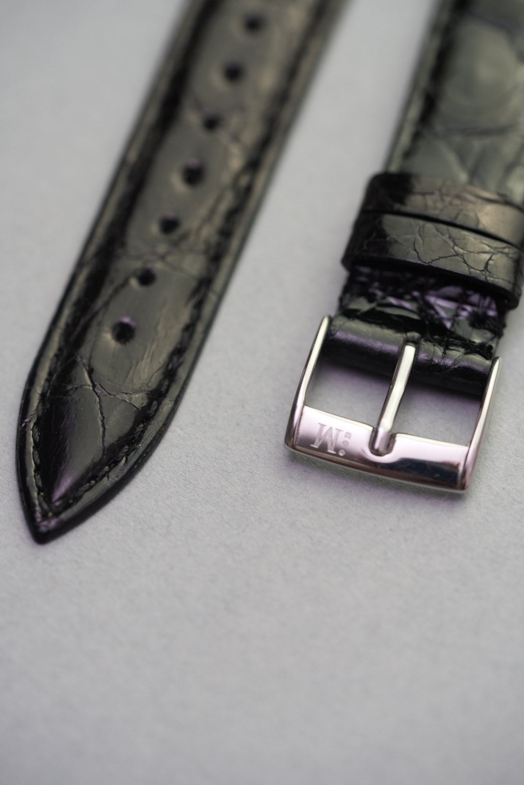 Detail shot of the polished stainless steel buckle and pointed tip on the Noir crocodile strap, designed for Cartier.