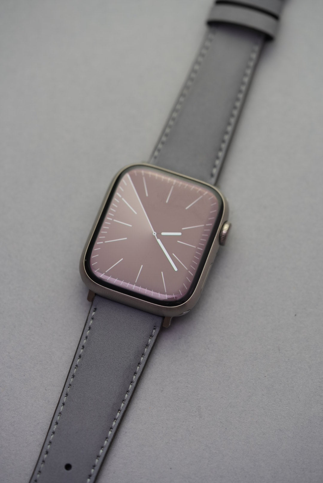 Close-up of grey nubuck strap with Apple Watch adapters, showing soft leather texture and stitching detail.