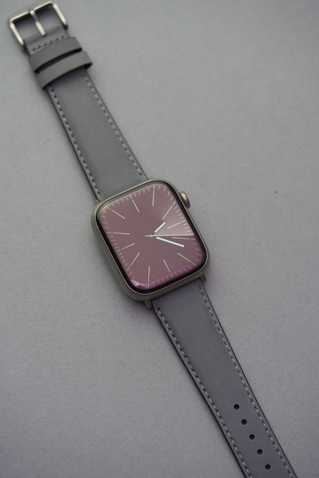 Close-up of grey nubuck strap with Apple Watch adapters, showing soft leather texture and stitching detail.