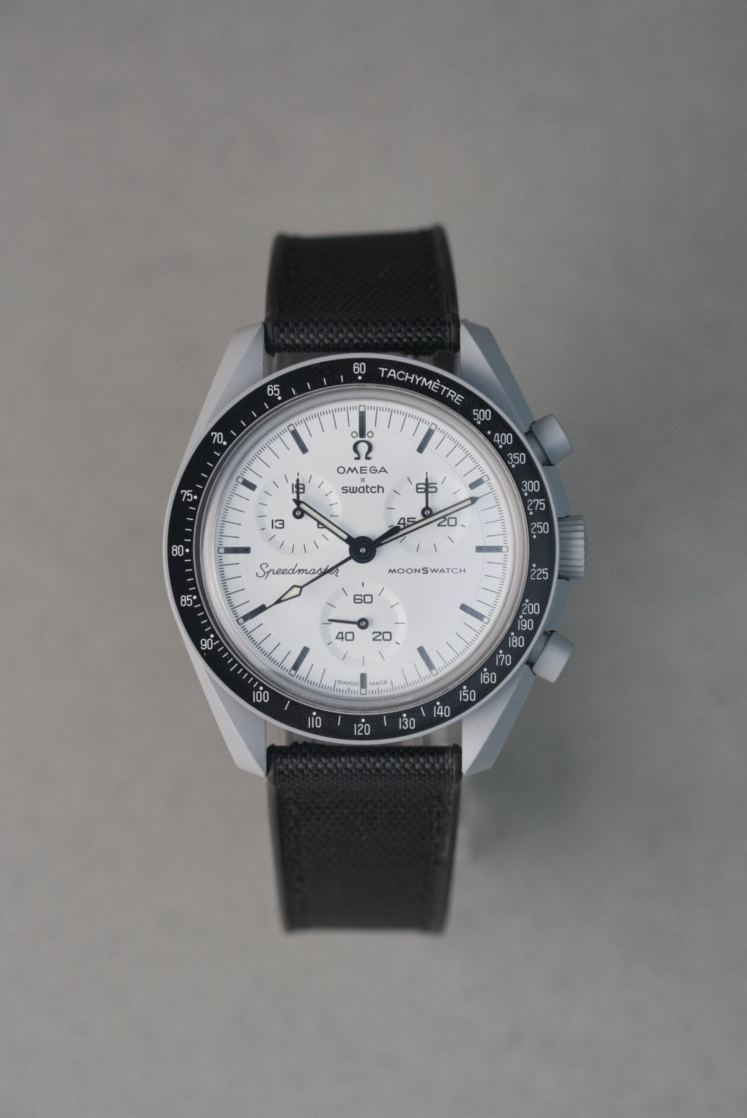 Wristwatch with a black strap and white face on a gray background