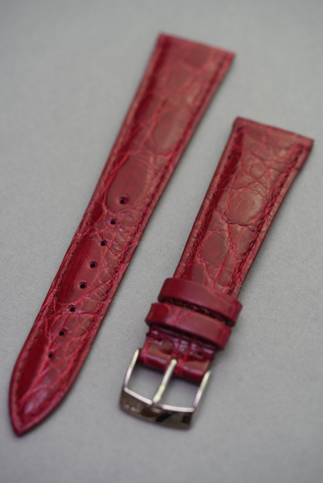 Full view of ruby red crocodile leather watch strap for Cartier, with natural scale detail and polished stainless steel buckle.