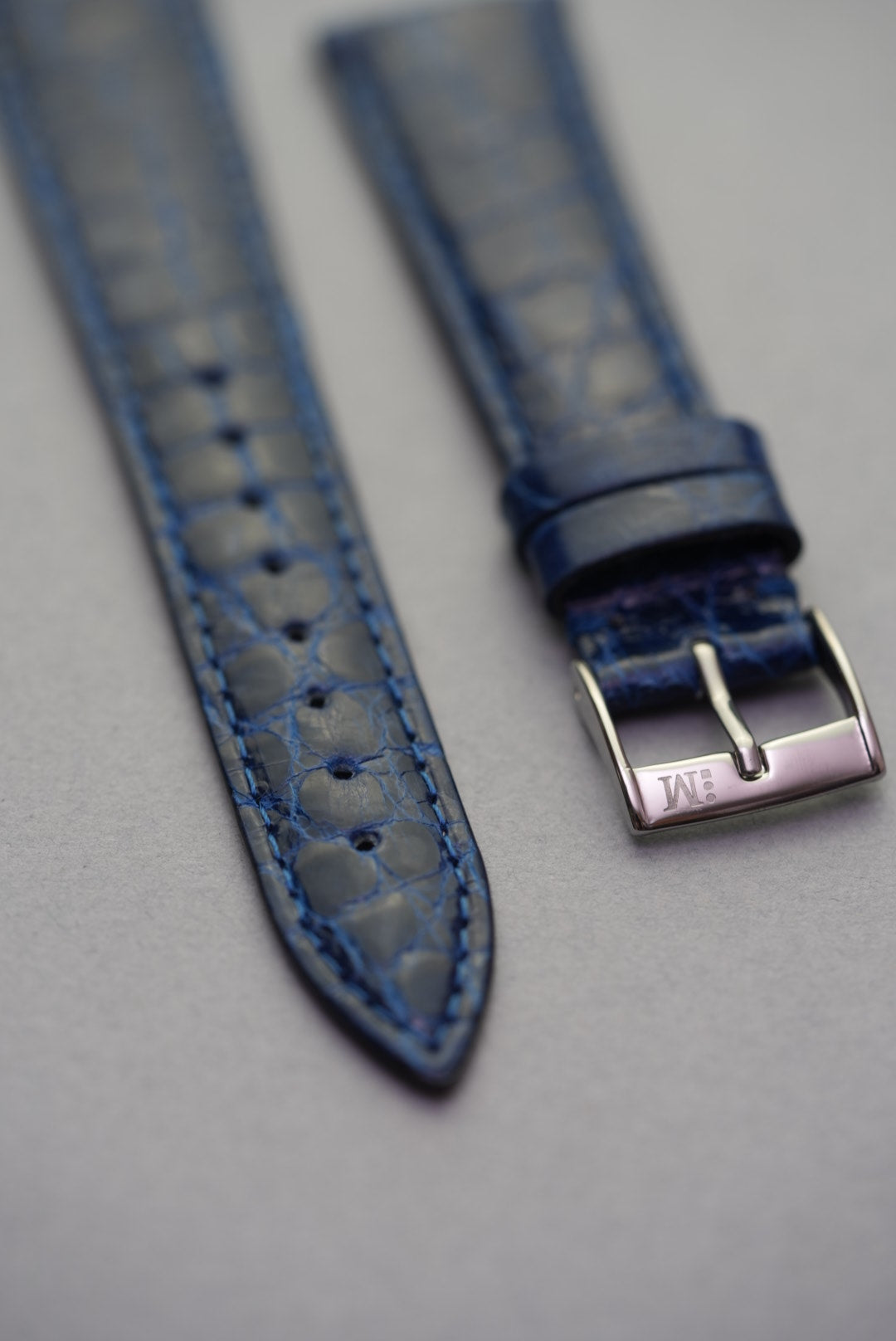 Close-up of polished buckle and pointed tip on sapphire crocodile watch strap for Cartier, highlighting the clean stitching and gloss.