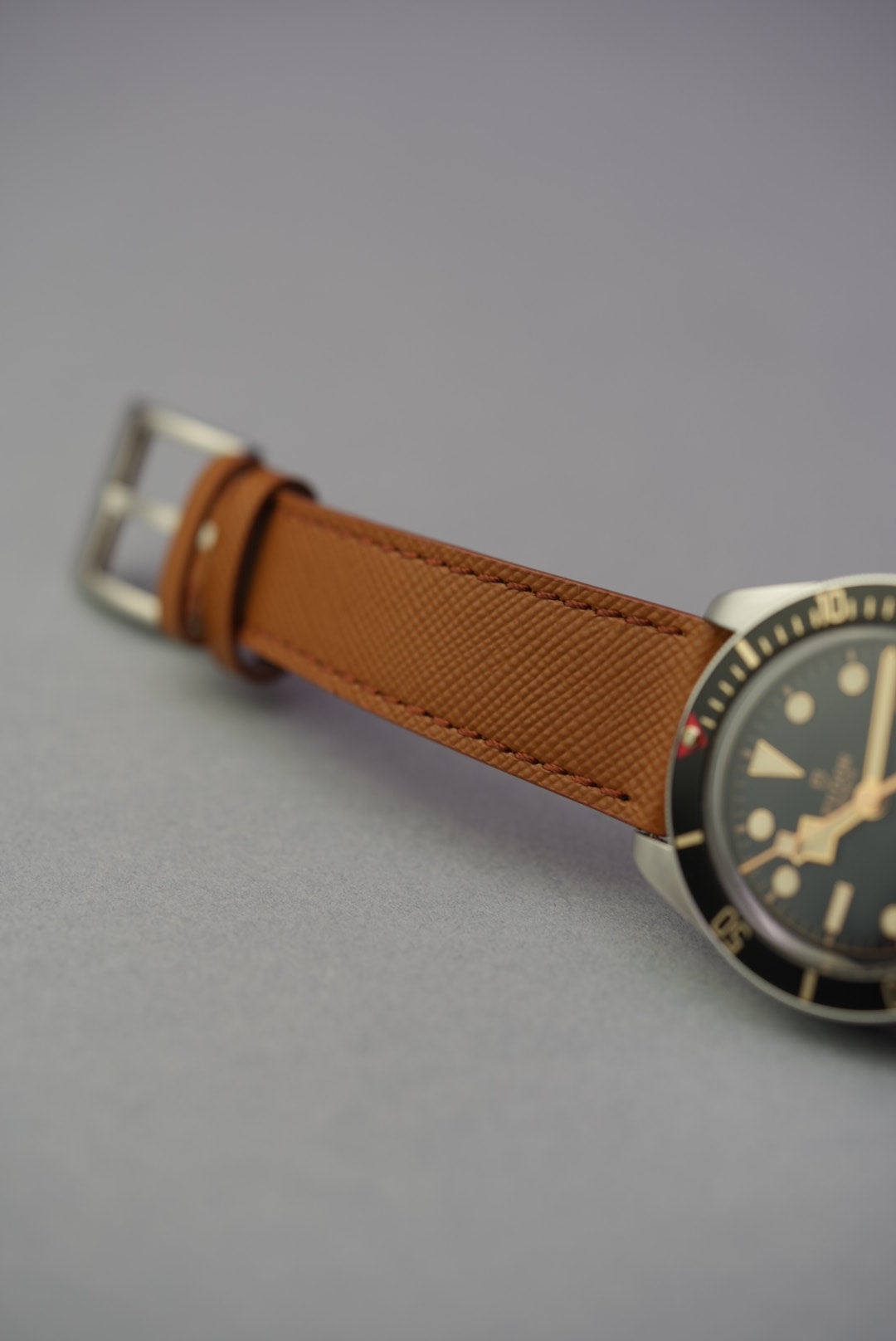Close-up of a tan Saffiano leather strap on a Tudor dive watch, showing detailed texture and stitching.