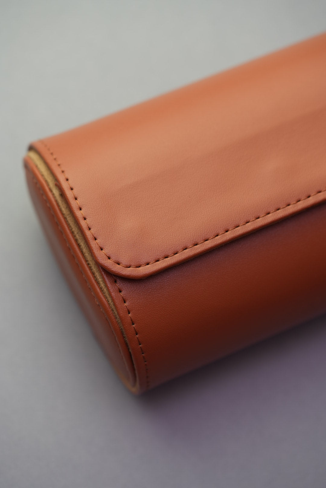 Close-up of stitching and end detail on closed three-slot tan watch roll.