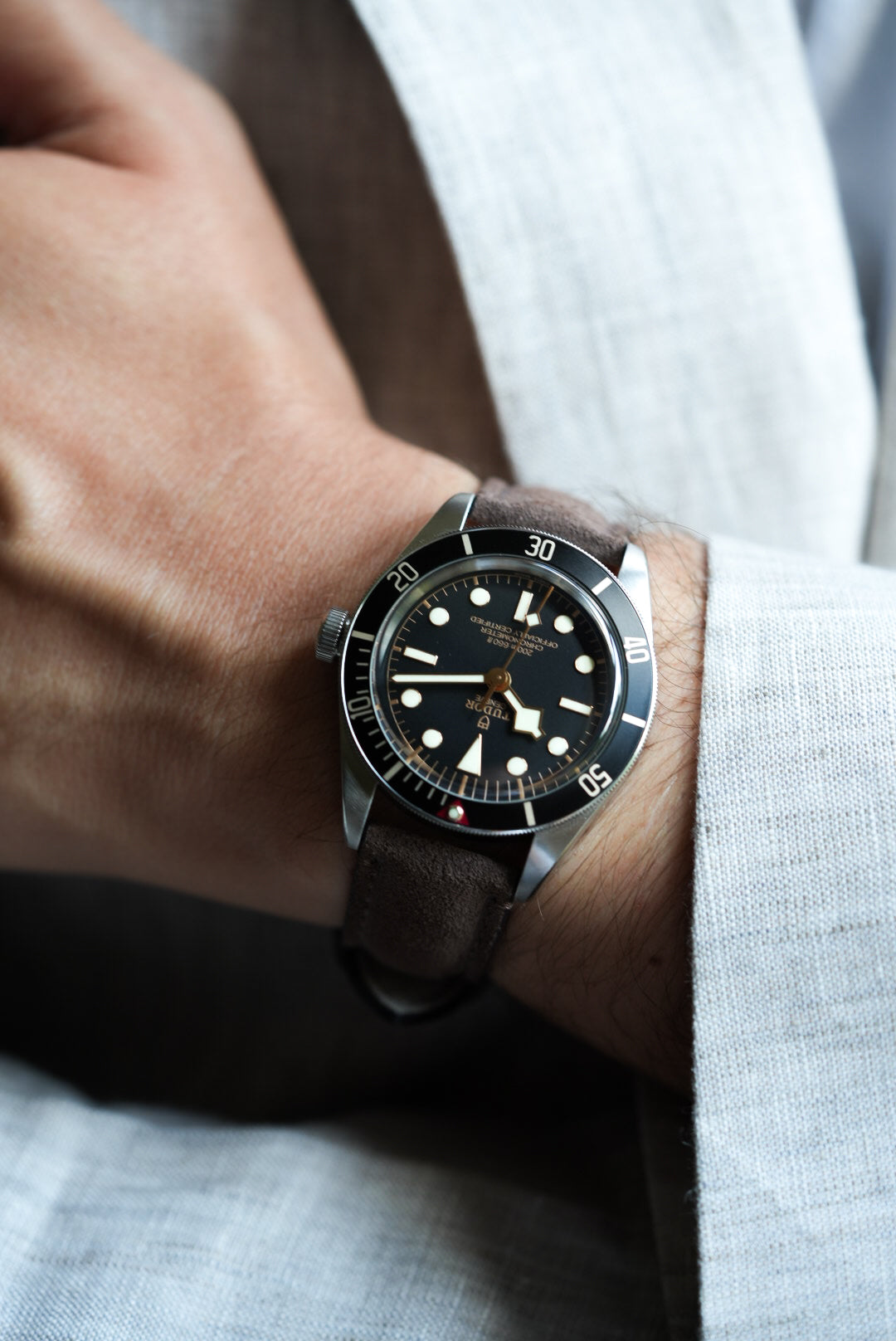 Close-up of Tudor Black Bay 58 with brown suede leather strap and linen cuff, classic styling