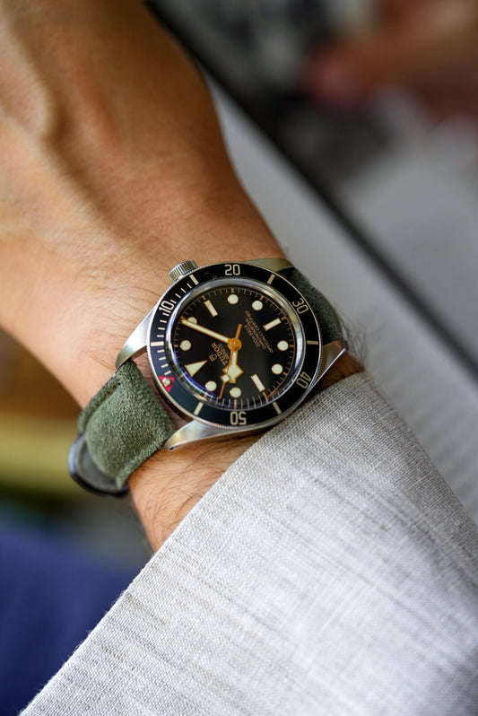 Tudor Black Bay watch fitted with green suede leather strap, worn with a light linen shirt