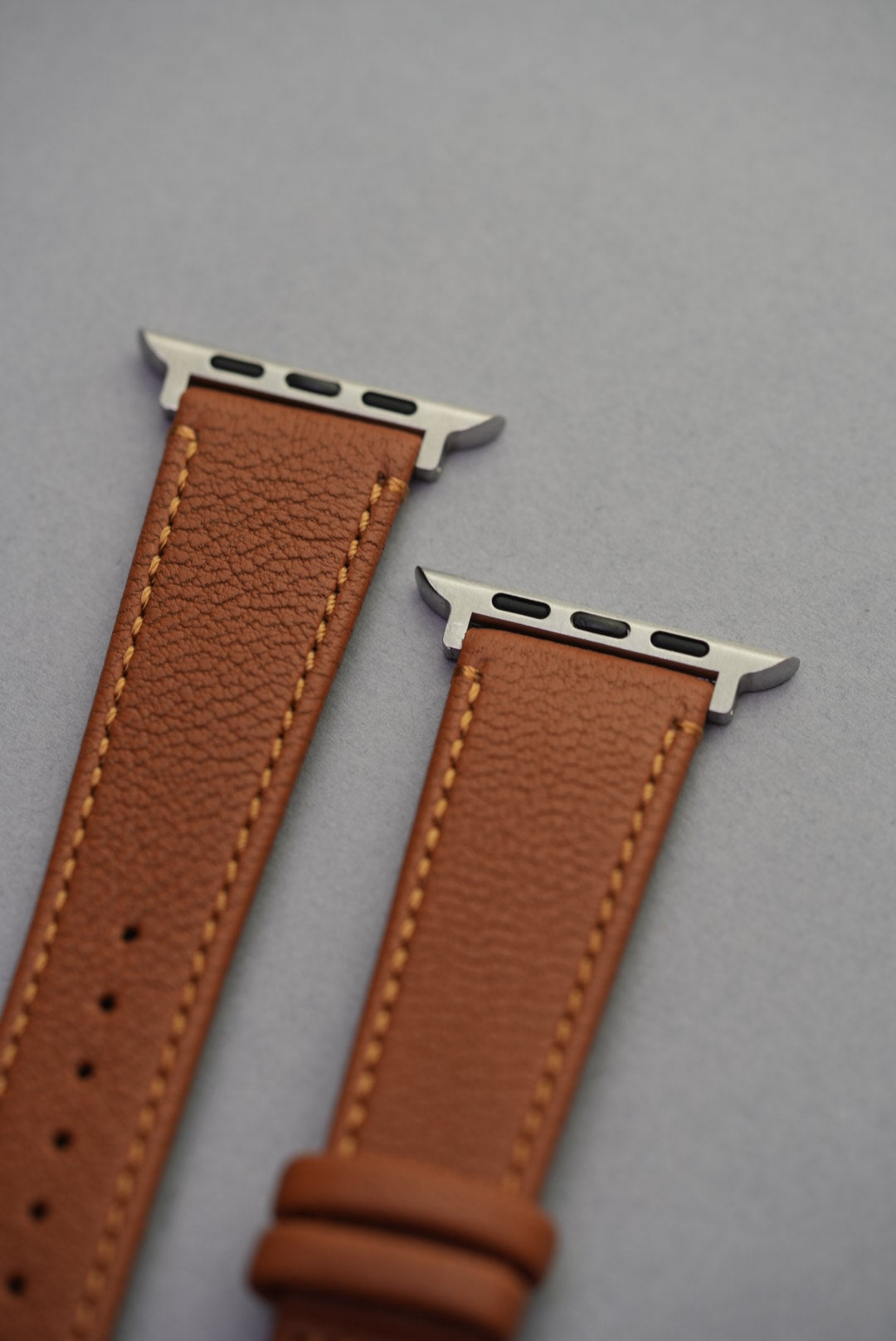 Detail view of Tuscan Sand strap adapters for Apple Watch, finished in stainless steel with smooth sheepskin grain.