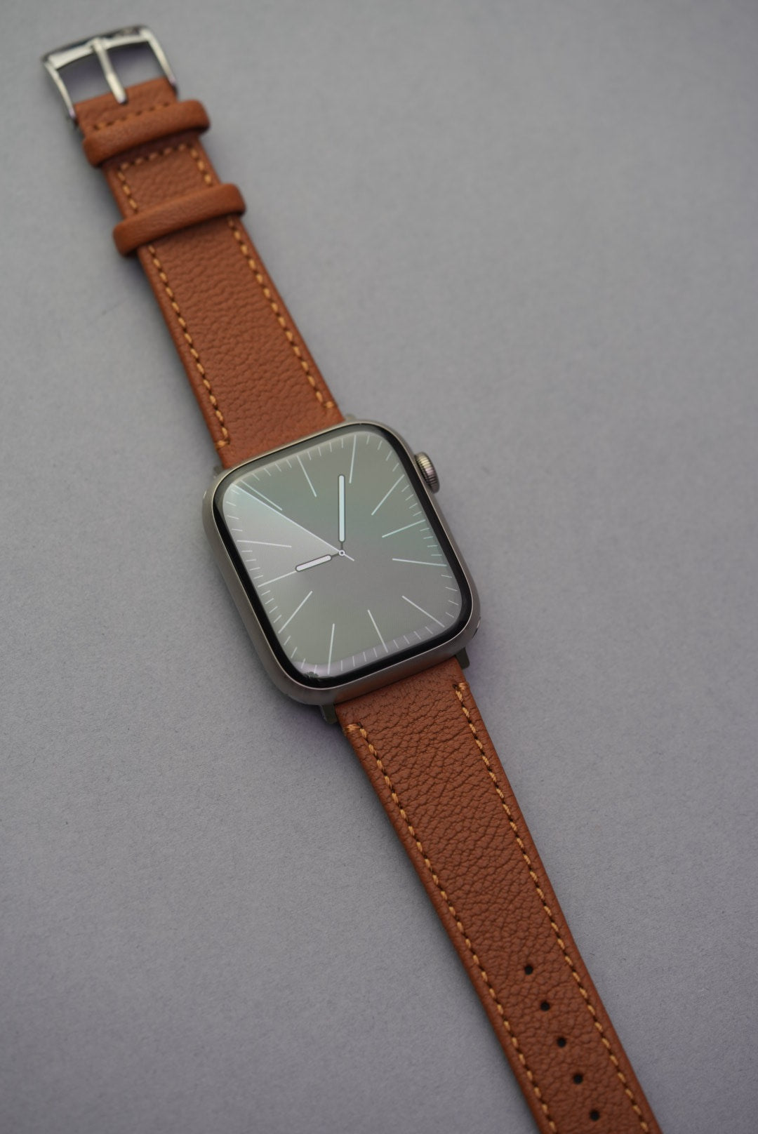Apple Watch with Tuscan Sand sheepskin strap in warm tan, shown full length with gold-toned stitching.