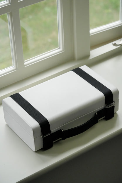 White box with black straps on a windowsill