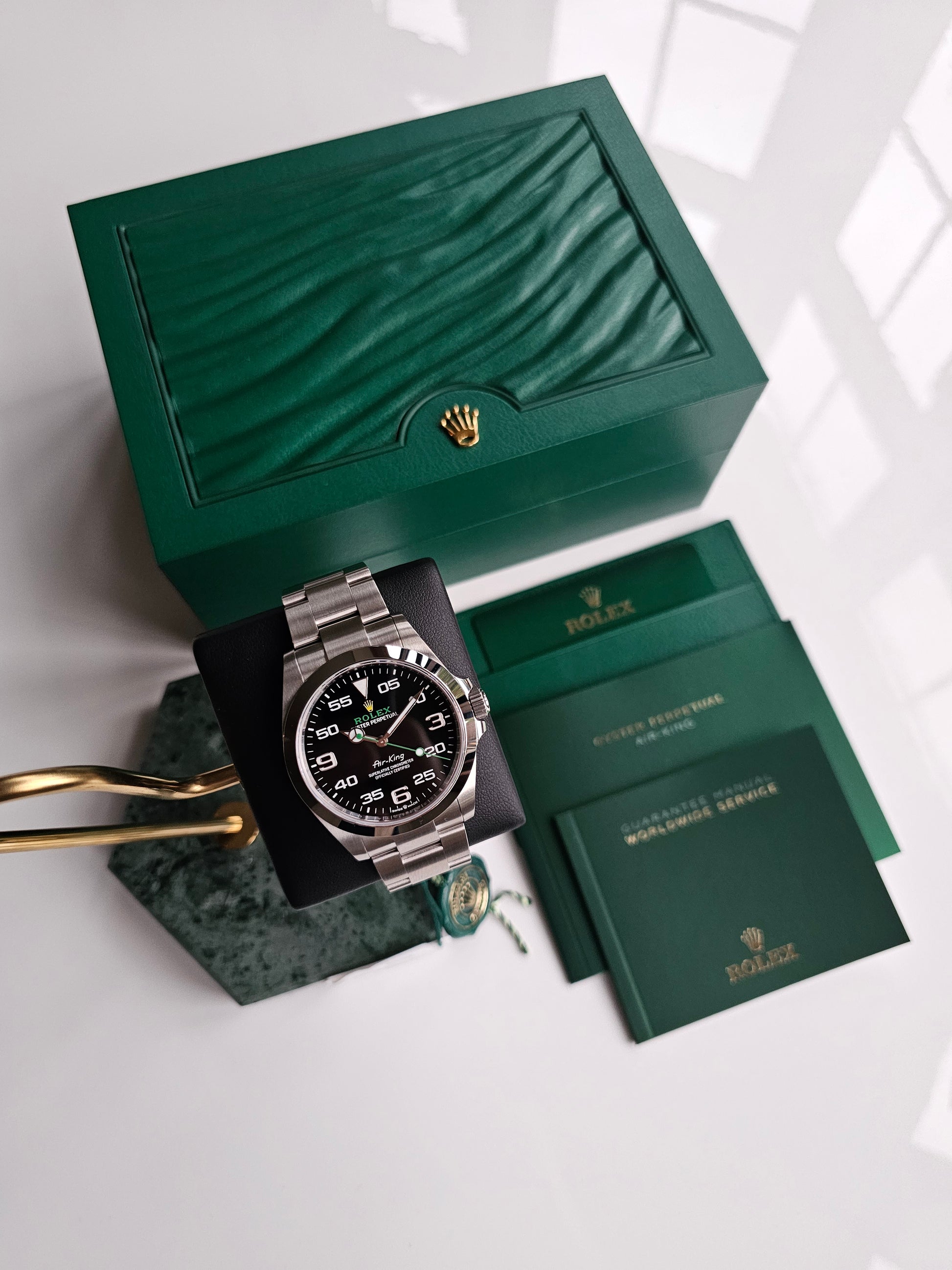 Rolex Airking 126900, Watch is displayed on a green watch stand, box and warranty documents are displayed
