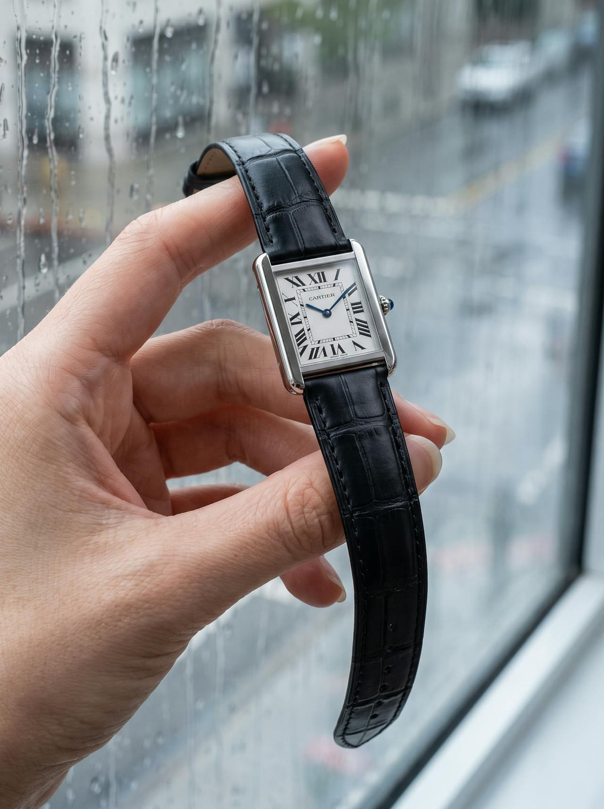 Cartier Tank Solo Small on a black square alligator-grain leather strap, held in hand