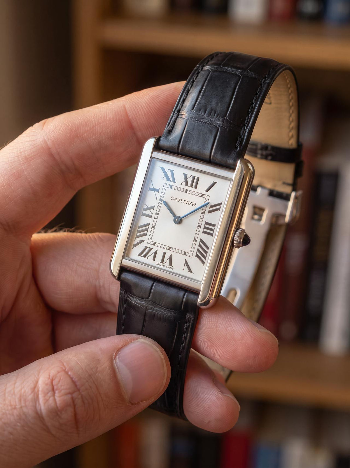 Cartier Tank Française on a black square alligator-grain leather strap, held in hand