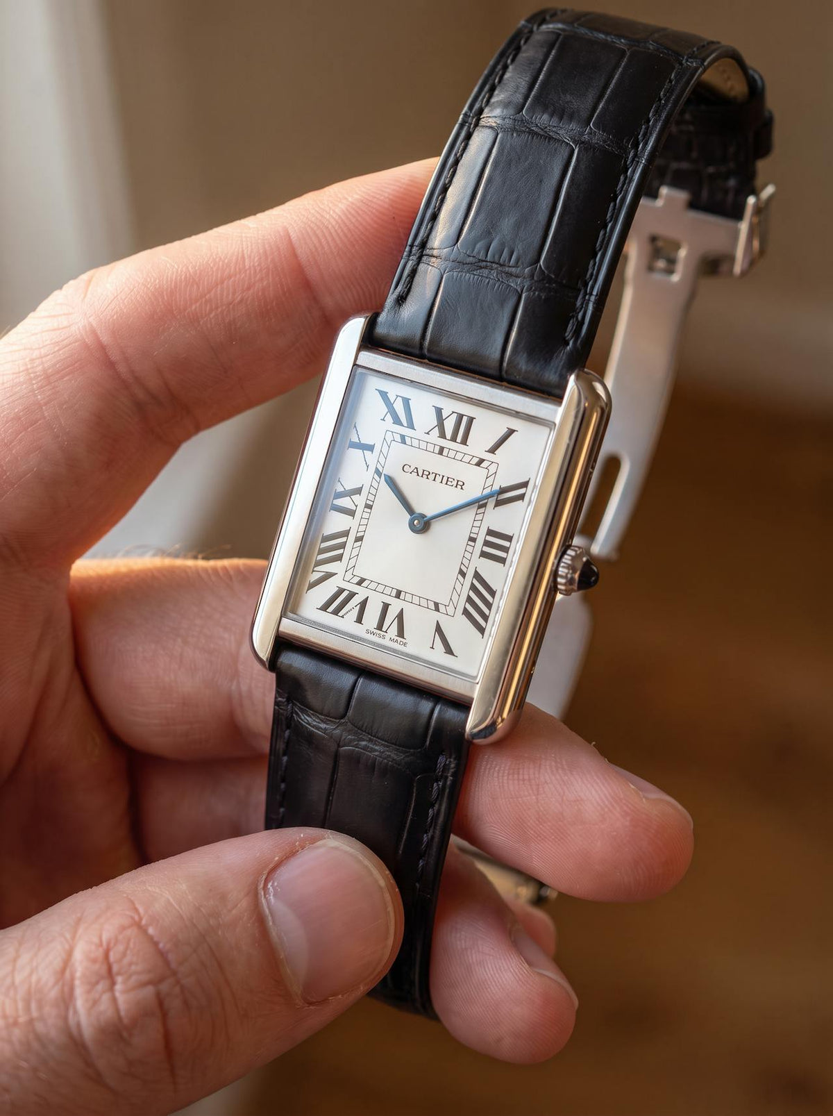 Cartier Tank Solo Large on a black square alligator-grain leather strap with folding deployant clasp, held in hand
