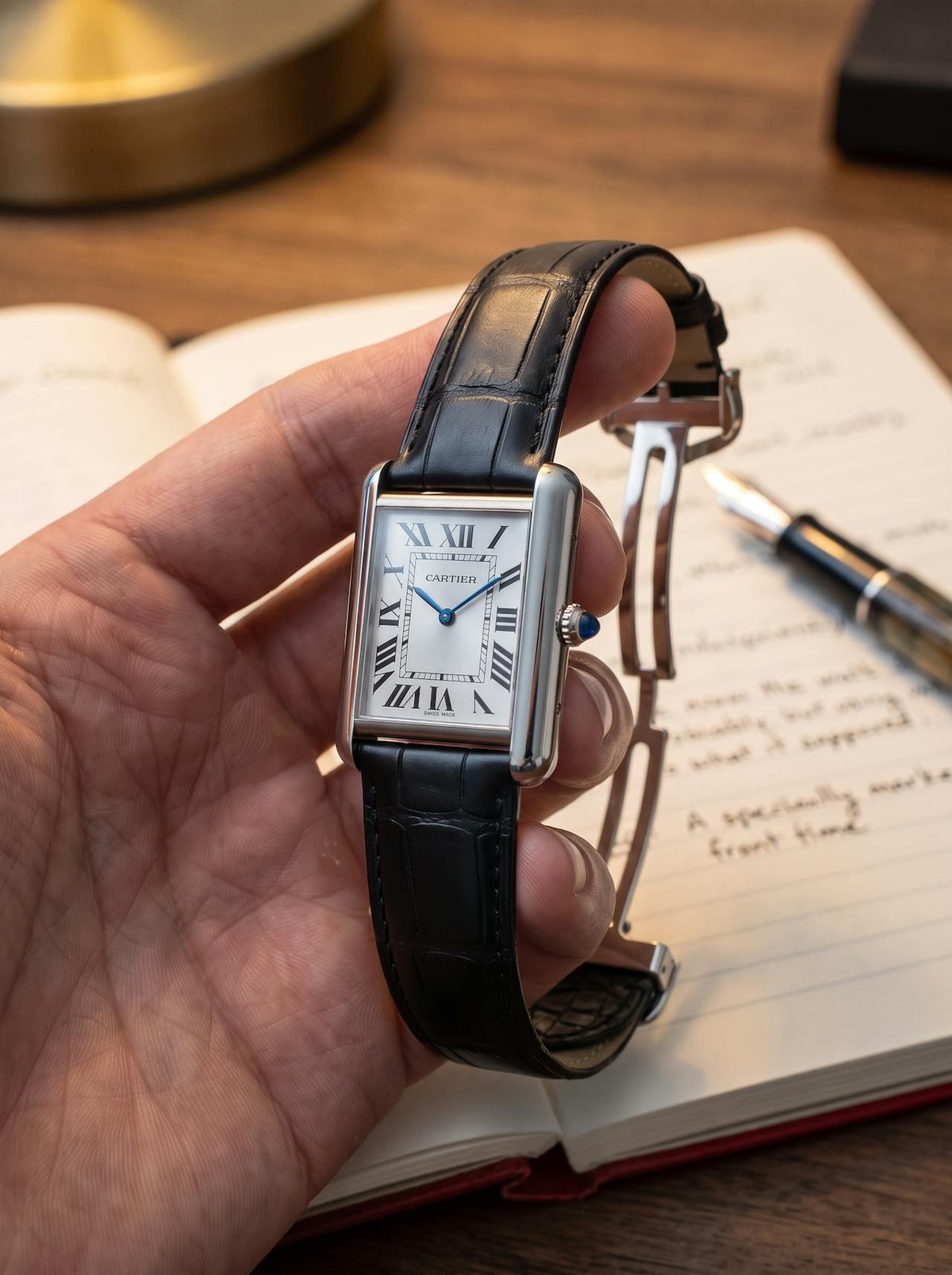 Cartier Tank Must Extra-Large on a black square alligator-grain leather strap, held in hand