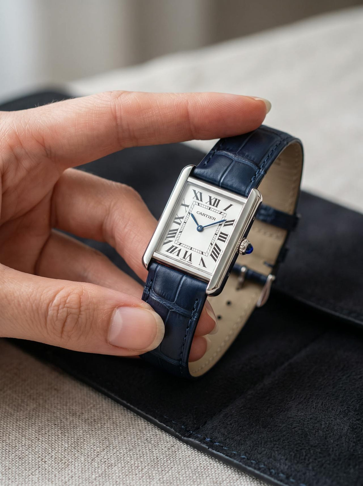 Cartier Tank Solo Small on a blue square alligator-grain leather strap, held in hand