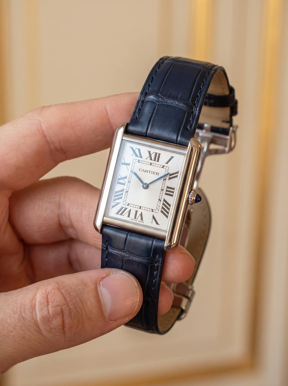 Cartier Tank Française on a blue square alligator-grain leather strap, held in hand