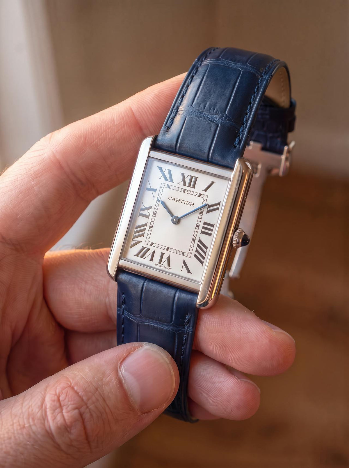 Cartier Tank Solo Large on a blue square alligator-grain leather strap with folding deployant clasp, held in hand