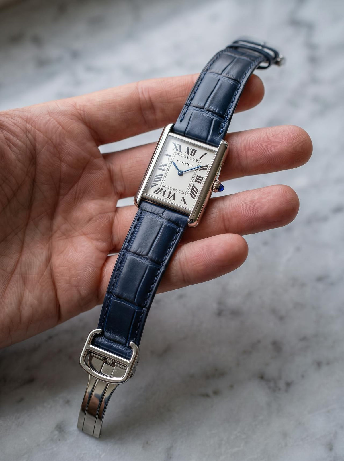 Cartier Tank Must Extra-Large on a blue square alligator-grain leather strap, held in hand