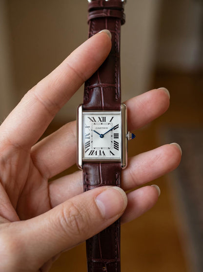 Cartier Tank Must Small on a brown square alligator-grain leather strap, held in hand