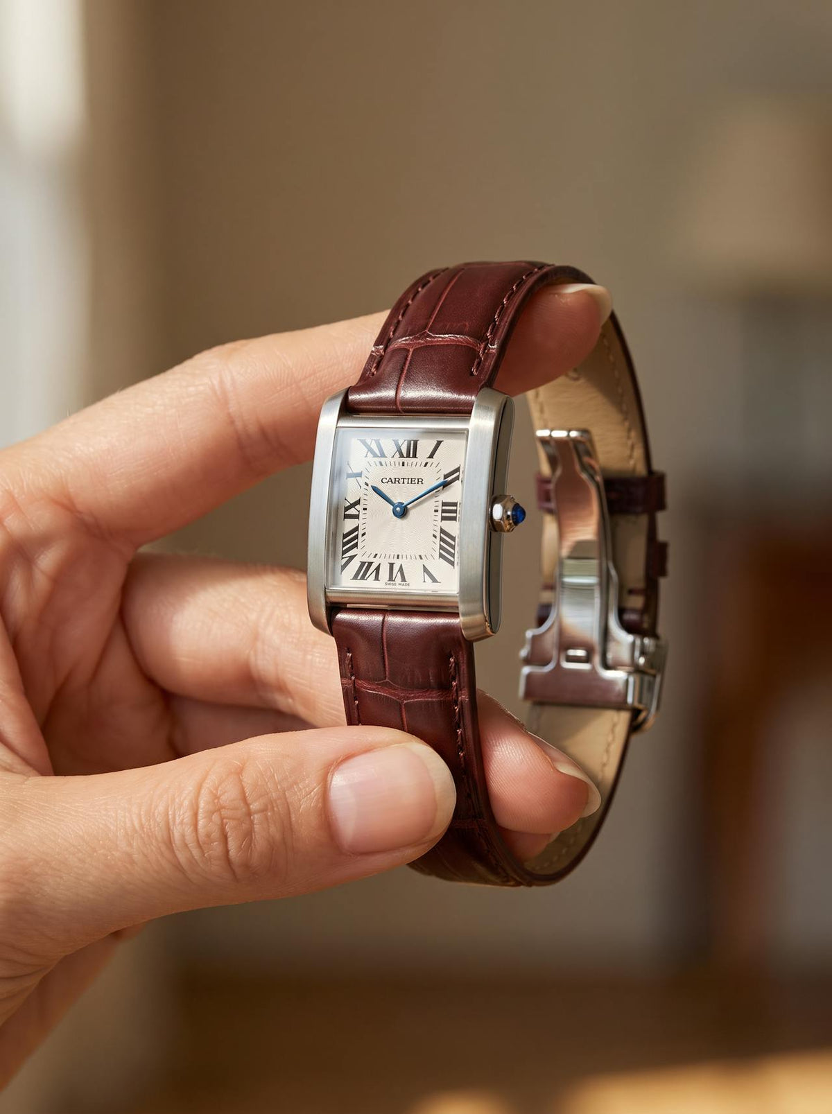Cartier Tank Française on a brown square alligator-grain leather strap, held in hand