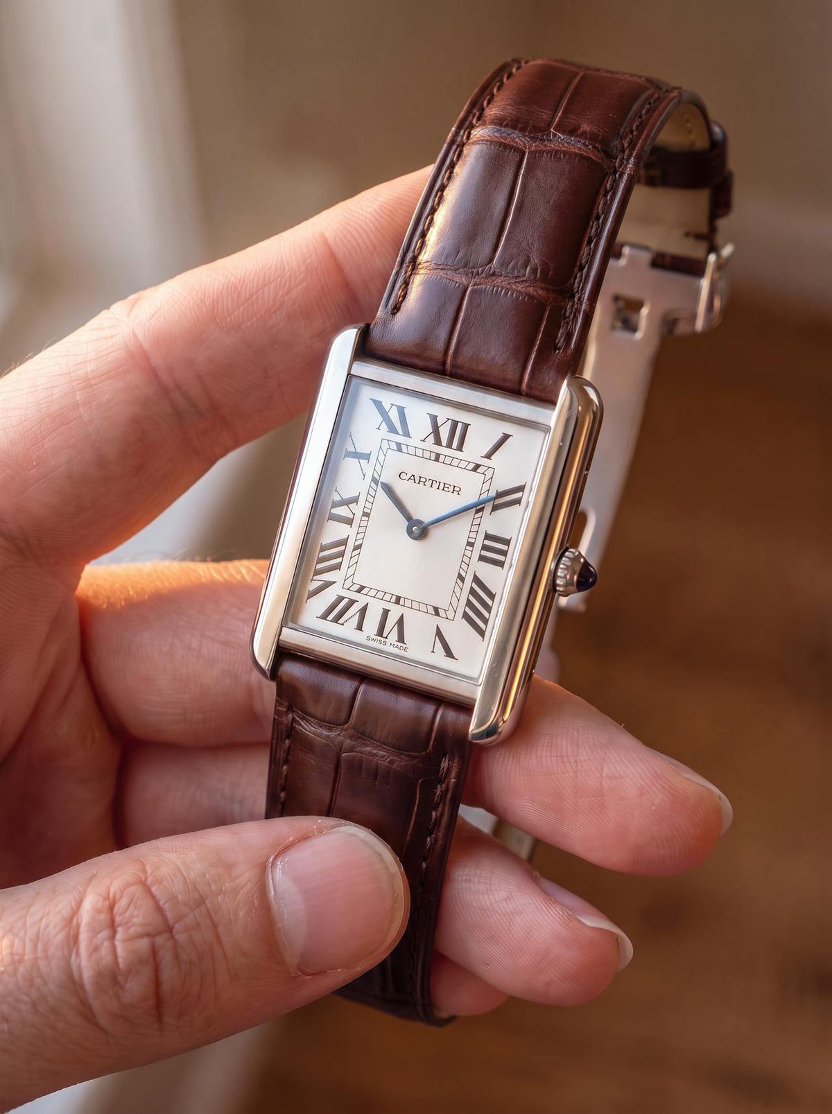 Cartier Tank Solo Large on a brown square alligator-grain leather strap with folding deployant clasp, held in hand