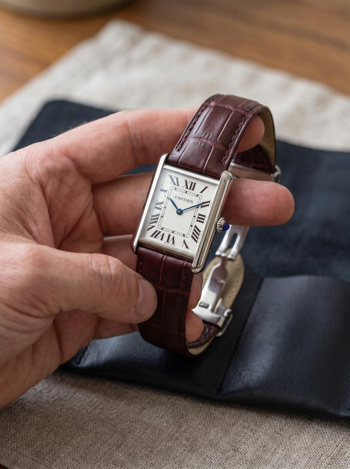 Cartier Tank Must Extra-Large on a brown square alligator-grain leather strap, held in hand