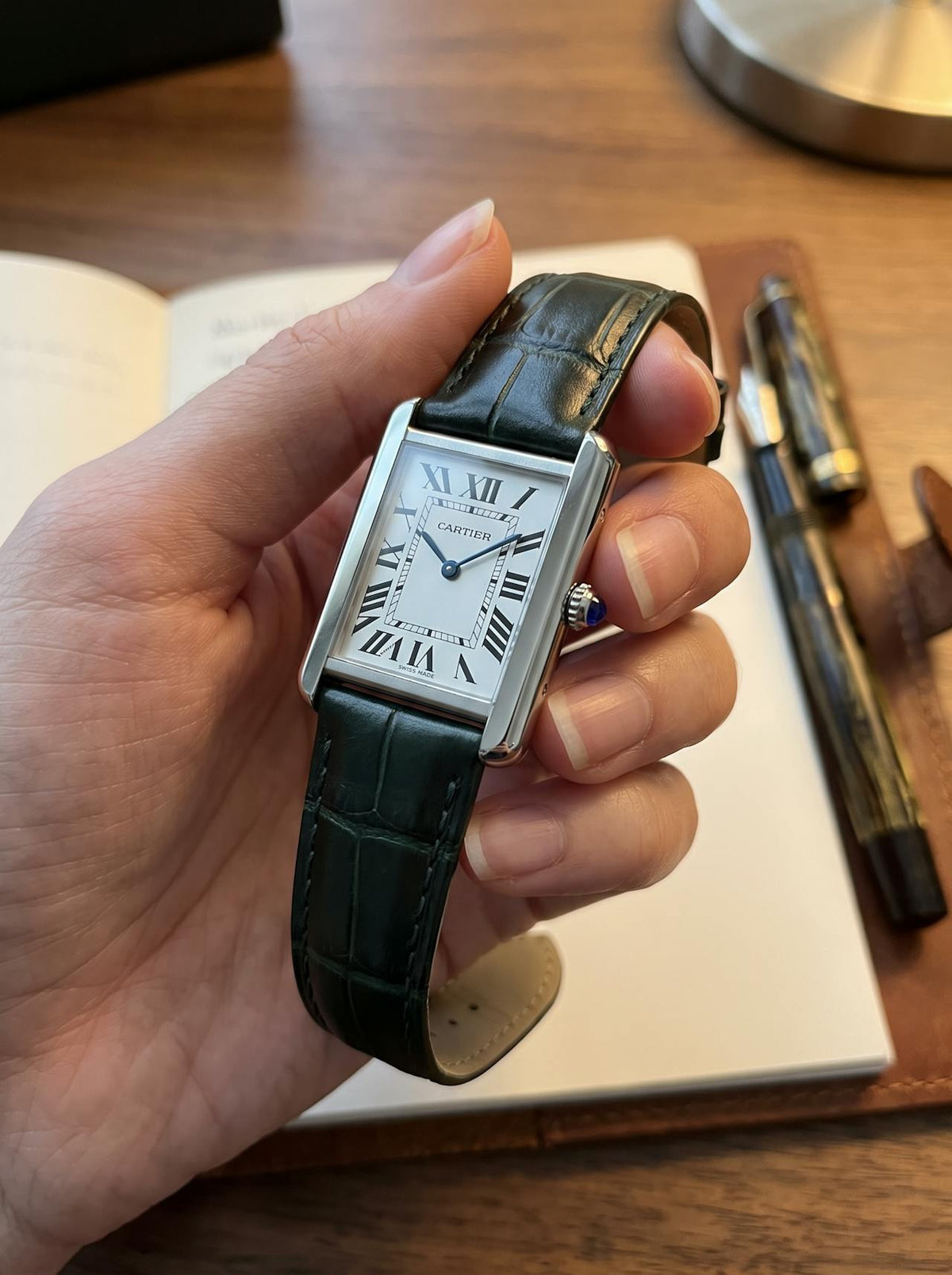 Cartier Tank Solo Small on a green square alligator-grain leather strap, held in hand