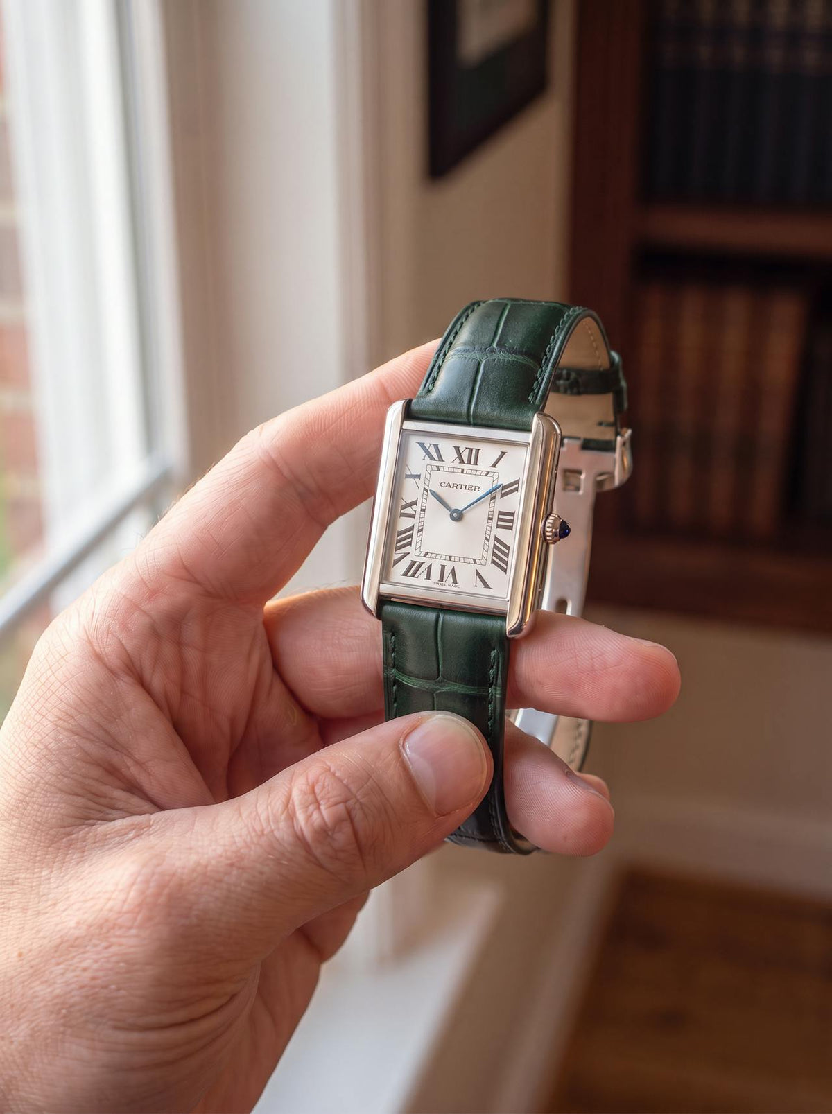 Cartier Tank Française on a green square alligator-grain leather strap, held in hand