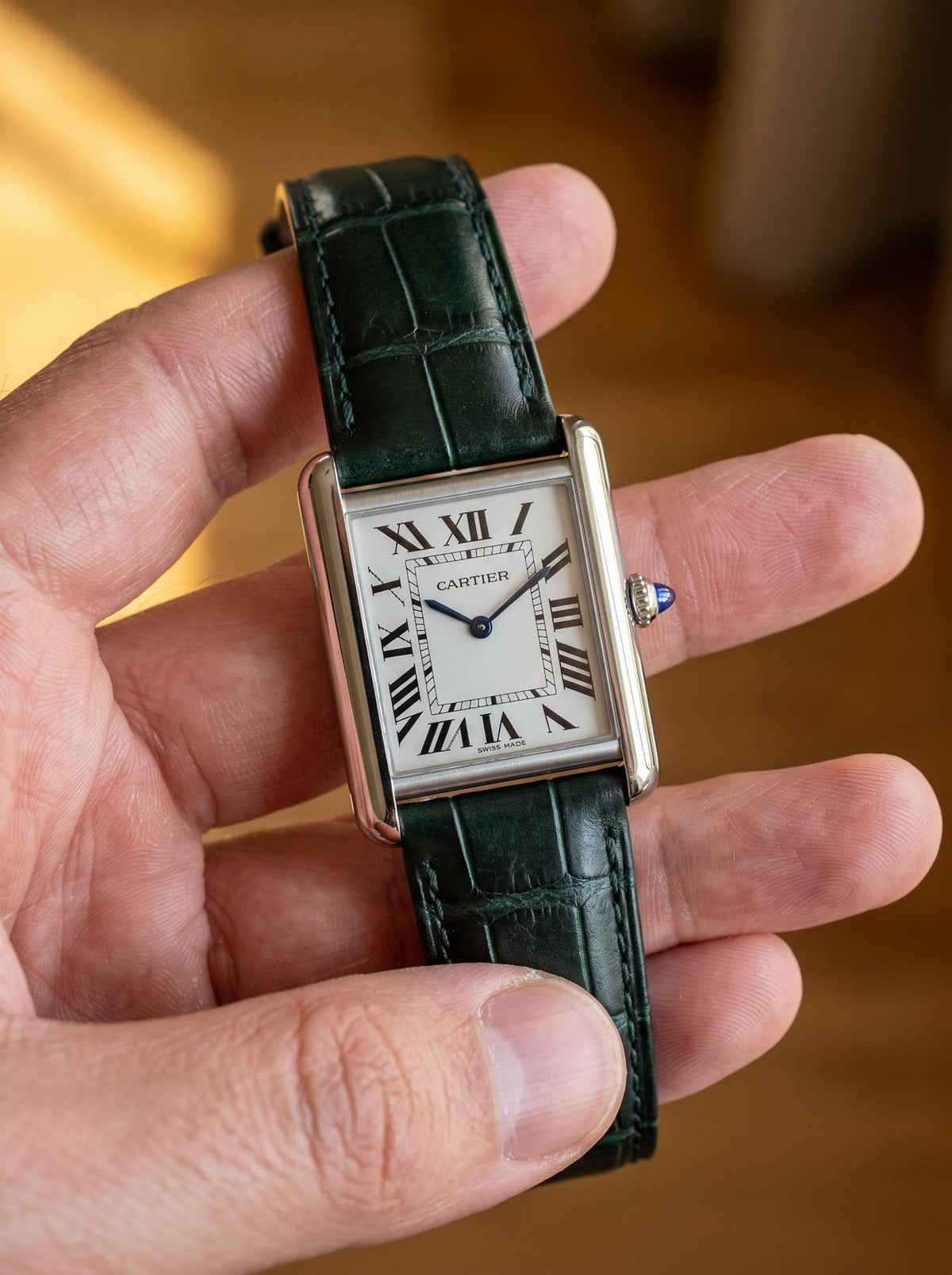 Cartier Tank Must Extra-Large on a green square alligator-grain leather strap, held in hand