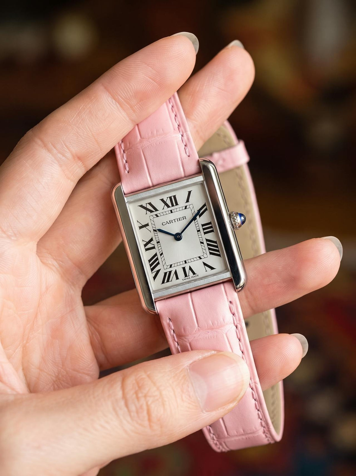 Cartier Tank Solo Small on a pink square alligator-grain leather strap, held in hand