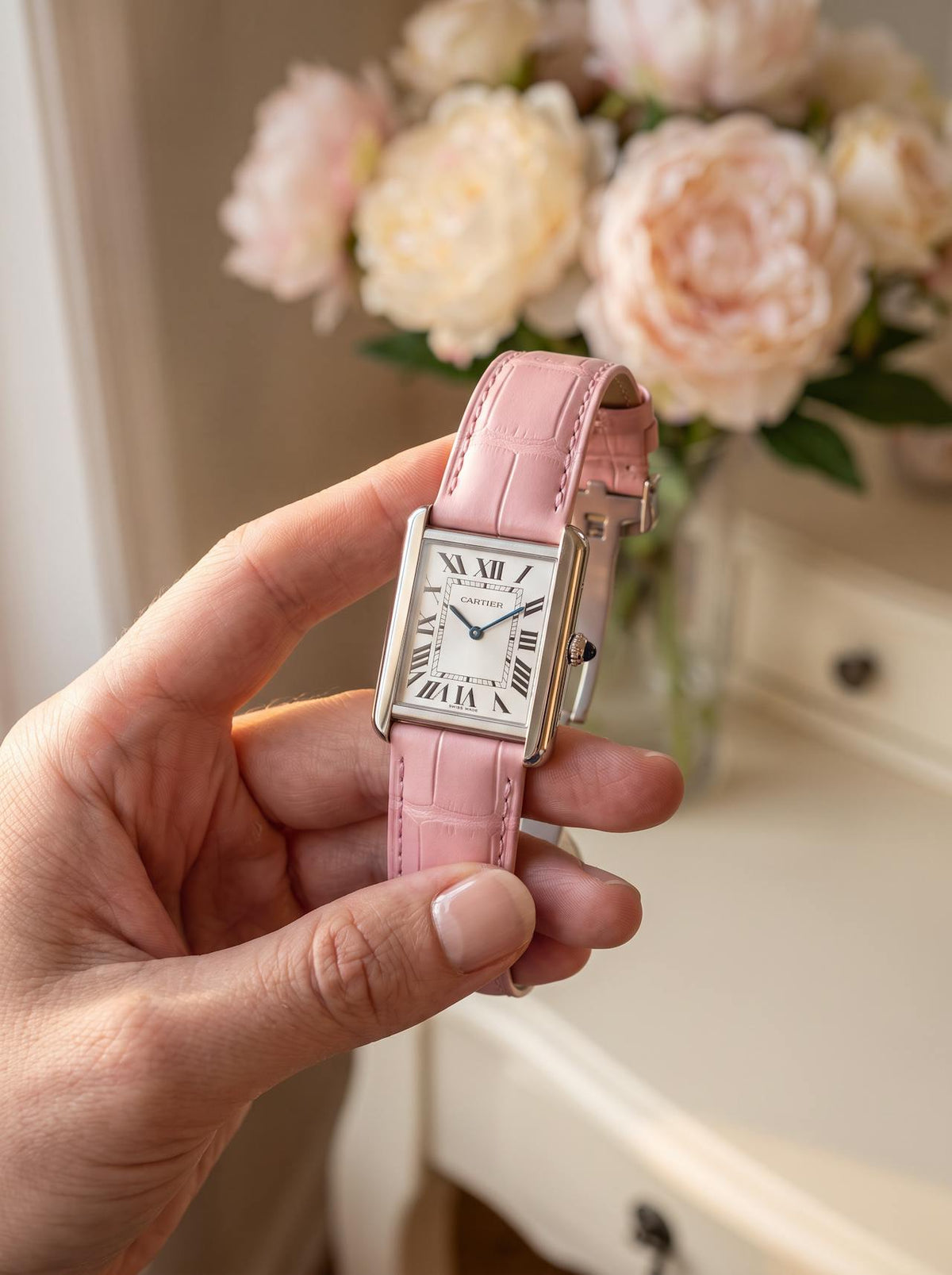 Cartier Tank Solo Large on a pink square alligator-grain leather strap with folding deployant clasp, held in hand