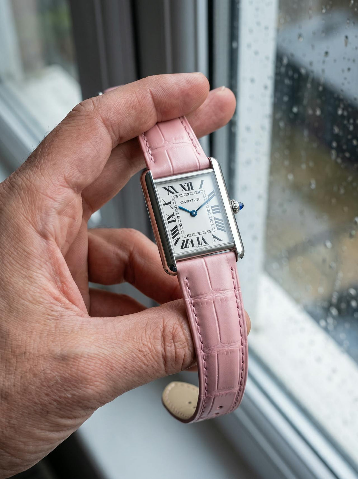 Cartier Tank Must Extra-Large on a pink square alligator-grain leather strap, held in hand