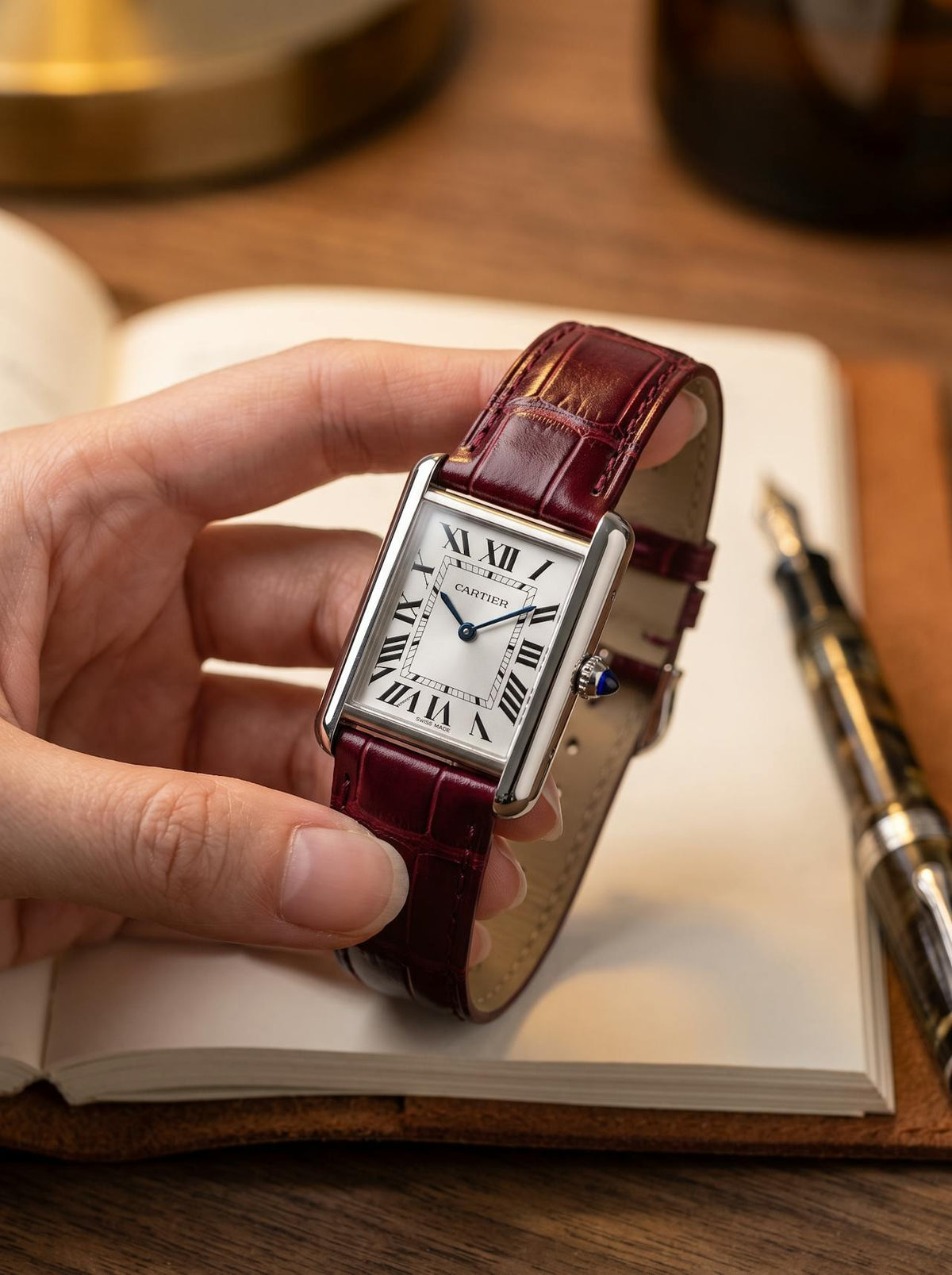 Cartier Tank Must Small on a red square alligator-grain leather strap, held in hand