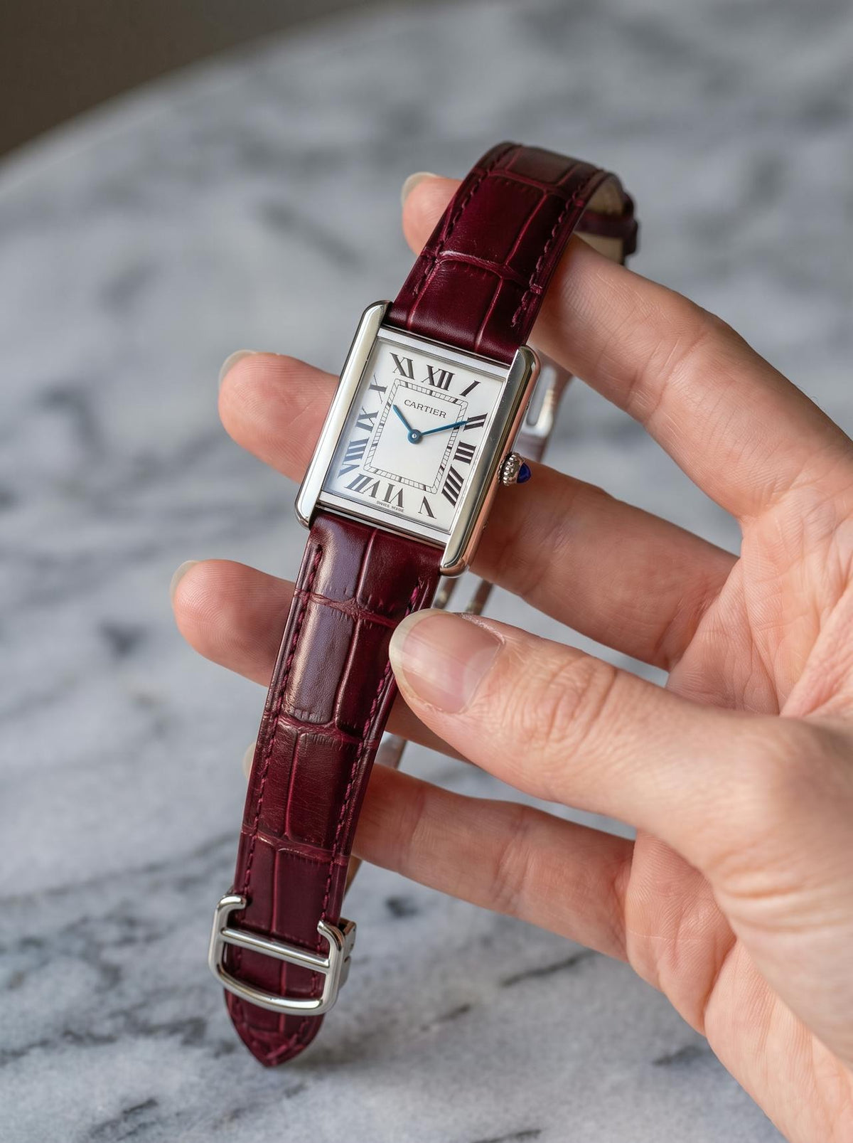 Cartier Tank Solo Small on a red square alligator-grain leather strap, held in hand