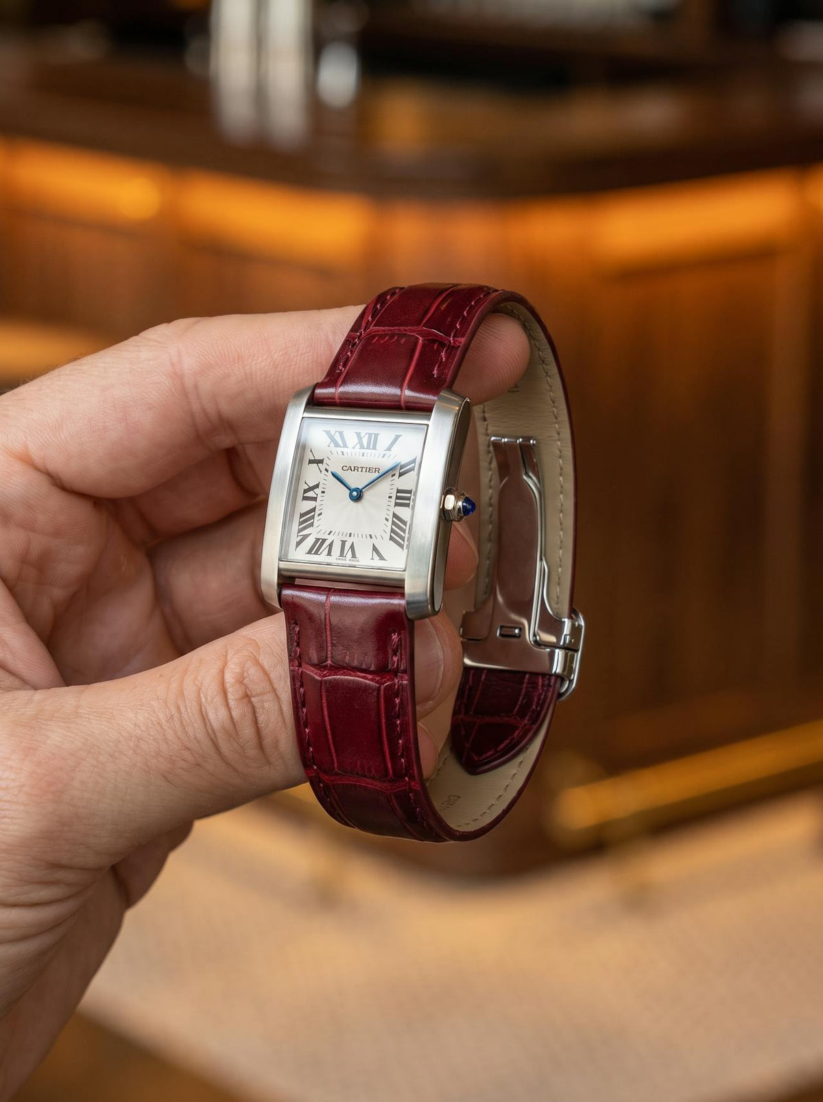 Cartier Tank Française on a red square alligator-grain leather strap, held in hand