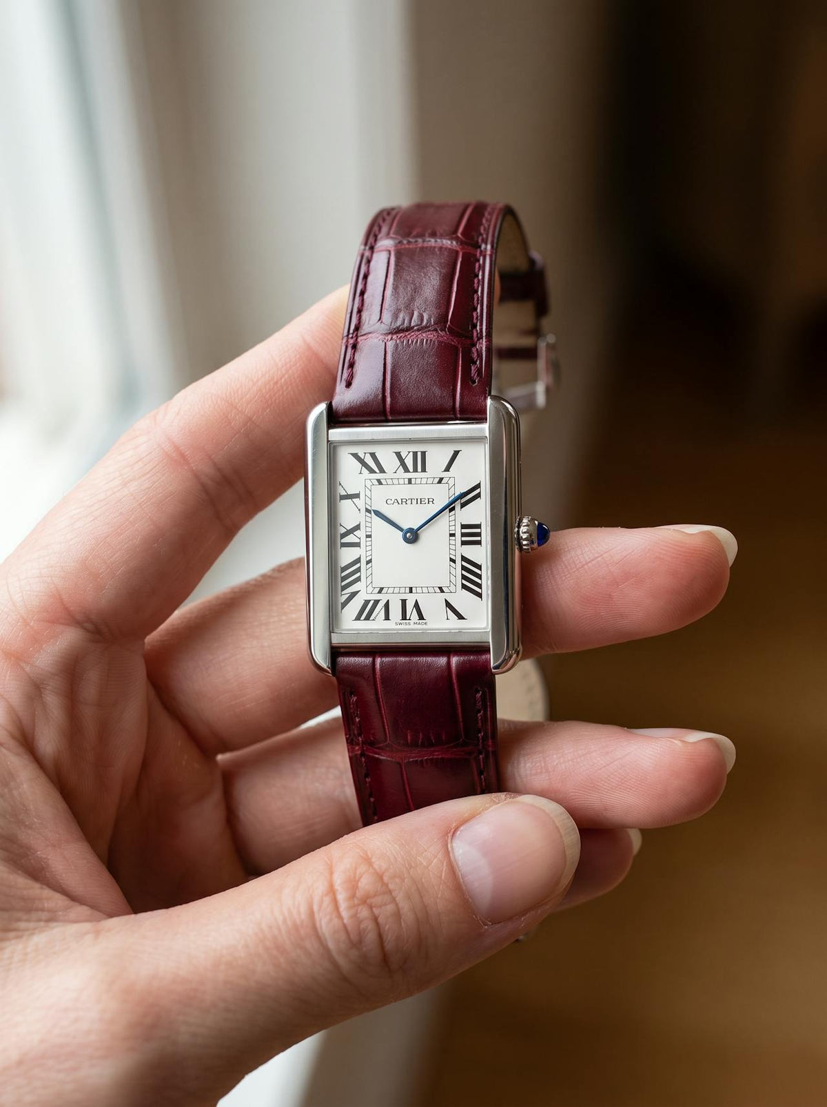 Cartier Tank Solo Large on a red square alligator-grain leather strap, held in hand