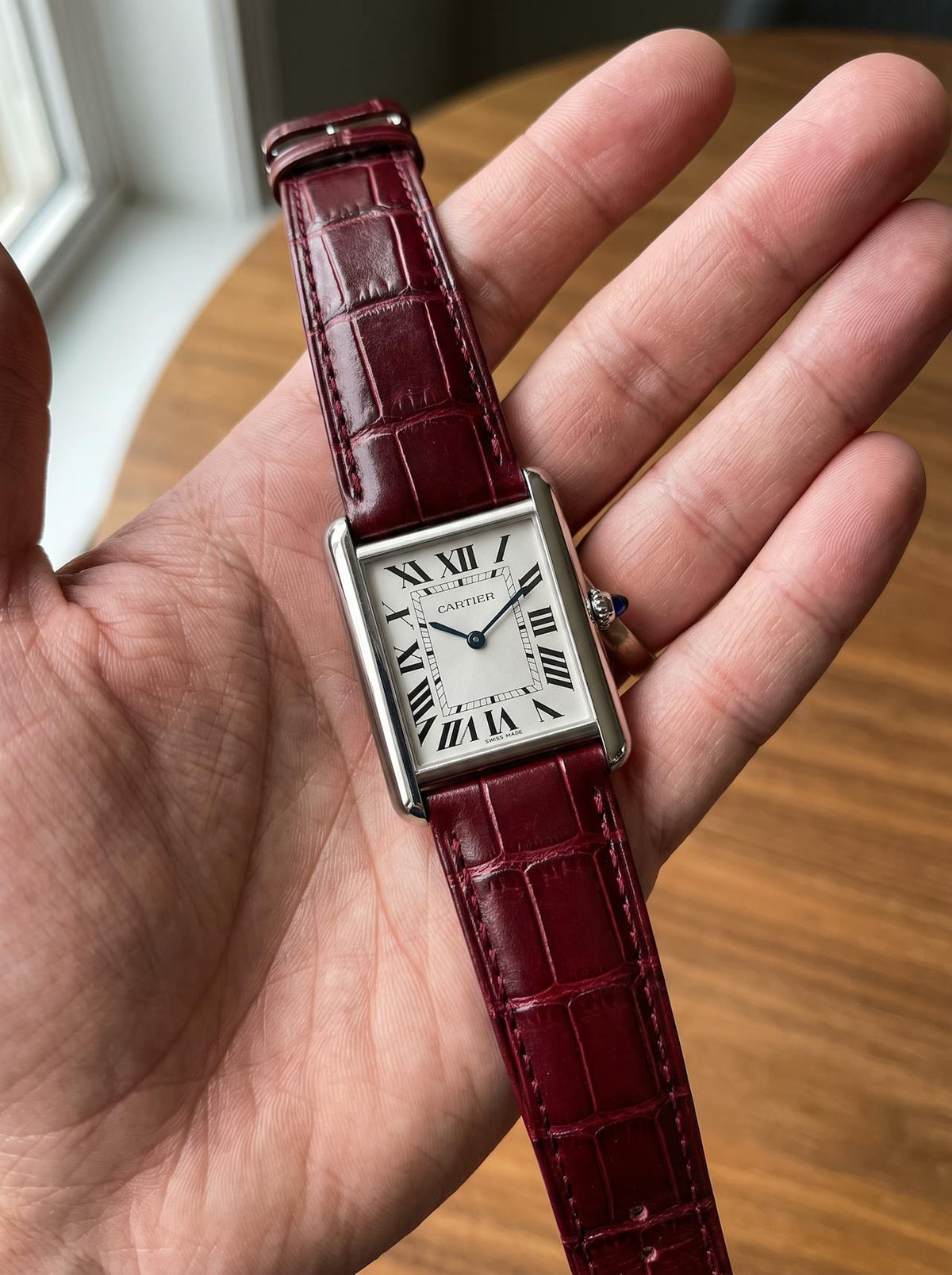 Cartier Tank Must Extra-Large on a red square alligator-grain leather strap, held in hand